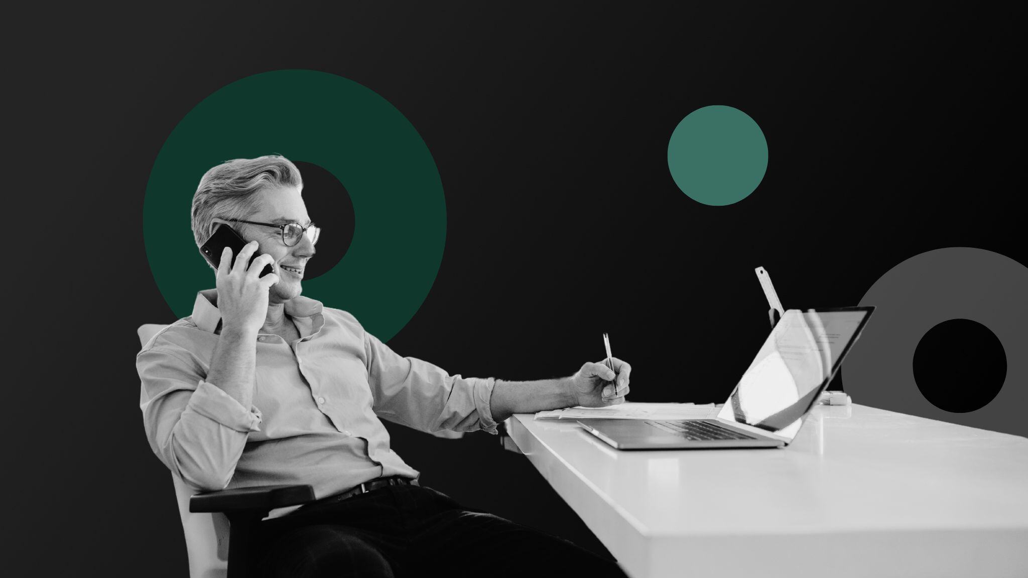 man-sitting-at-desk-in-front-of-laptop-talking-on-cell-phone